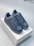Pair of dark charcoal Alexander McQueen low-top sneakers with broad laces and chunky tonal soles.