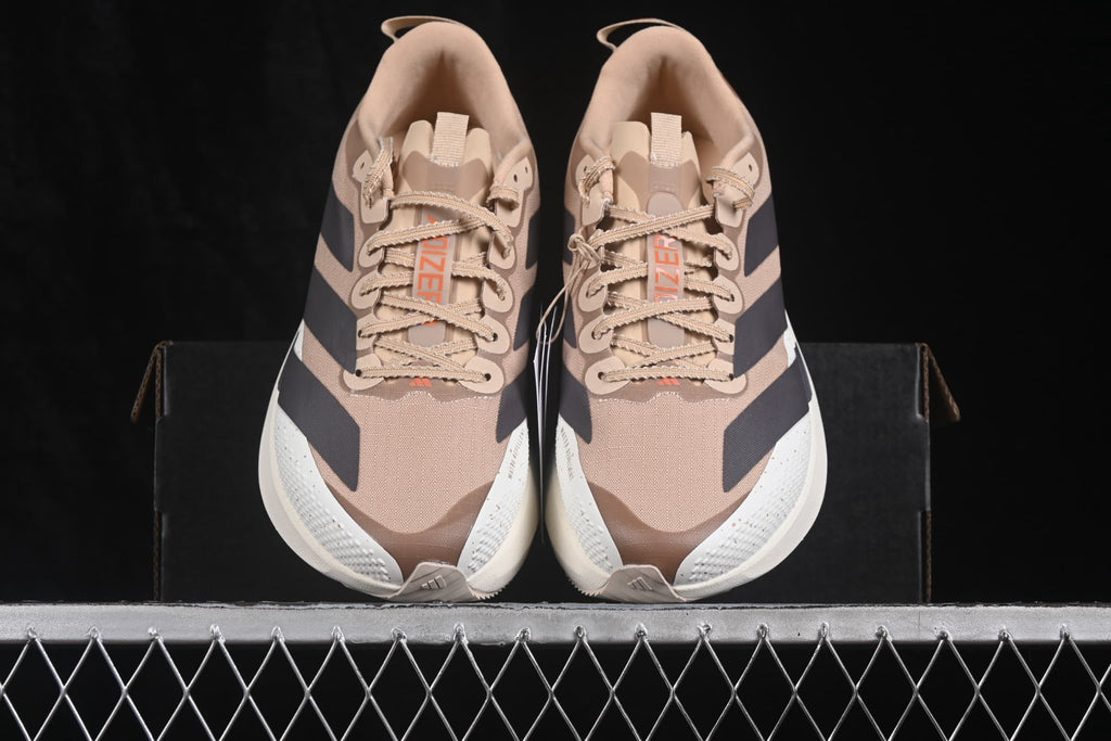 Top view of the pair showing the lace-up construction, beige upper, black stripe accents and Adizero tongue labels.