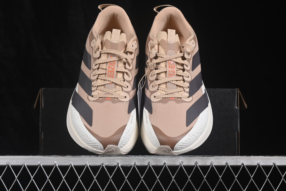 Top view of the pair showing the lace-up construction, beige upper, black stripe accents and Adizero tongue labels.