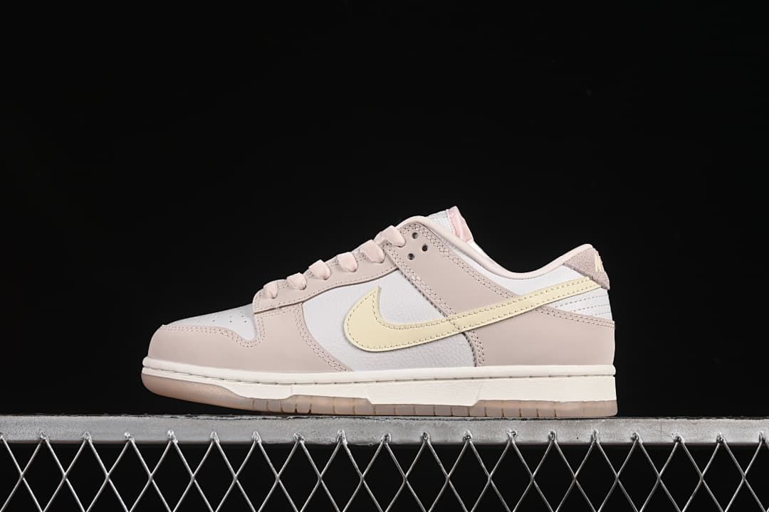 Side view of pink, white, and pale yellow Nike SB Dunk Low sneakers