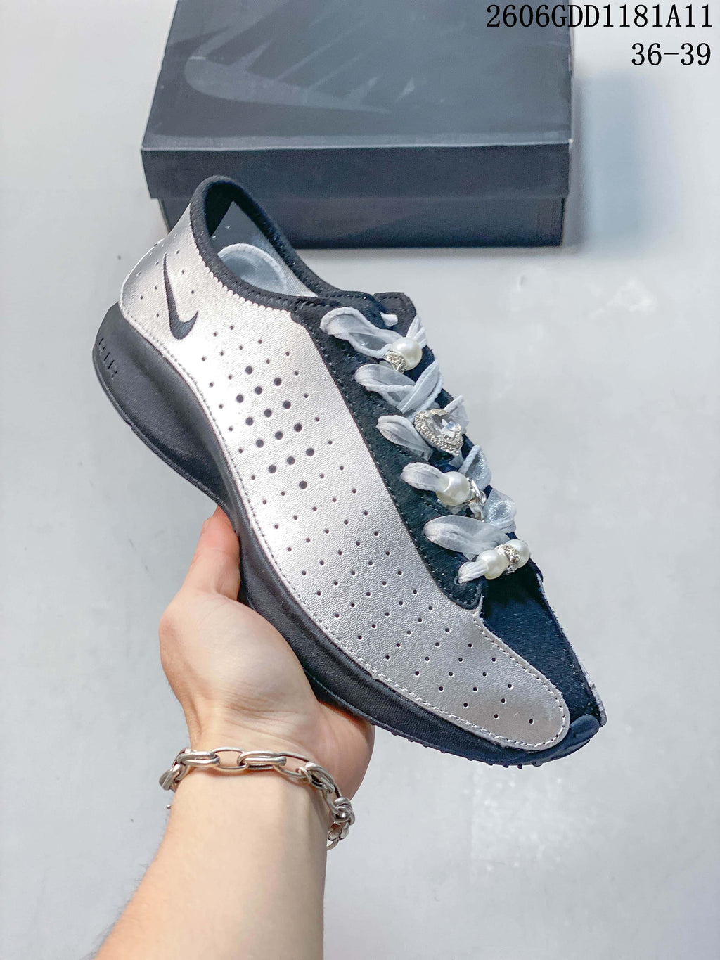 Side view of the silver and navy low-top sneaker with perforated panels and decorative laces.