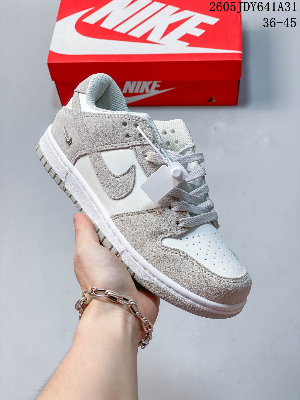 Angled view of a white and light grey low-top sneaker with side Swoosh detail