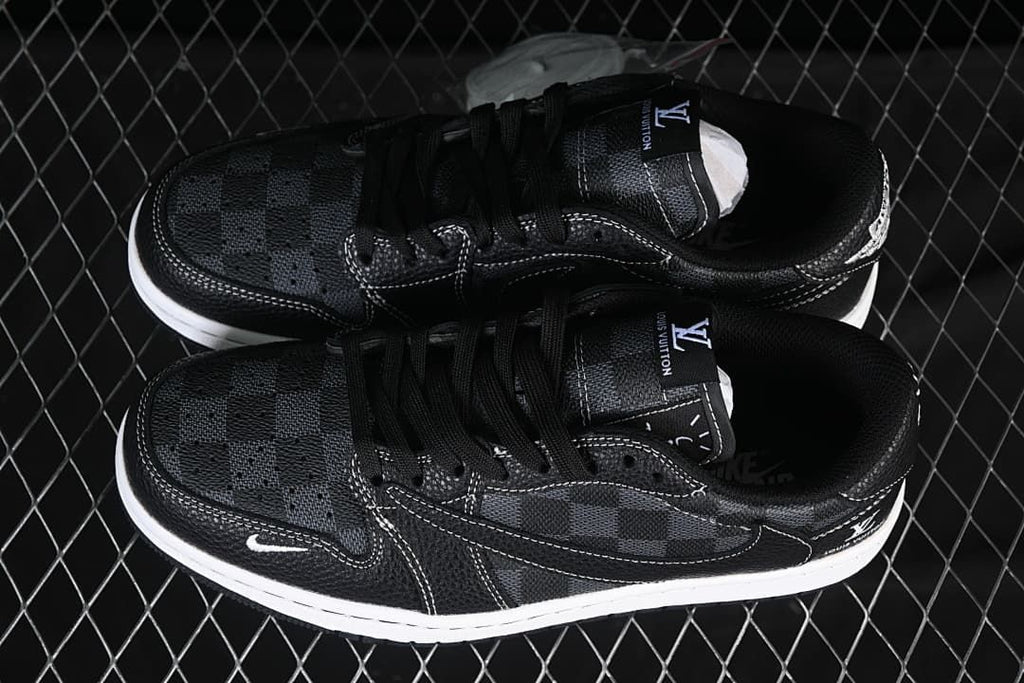 Overhead view of a pair of black low-top sneakers showing check-pattern toe and side panels, black laces, contrast stitching, and white midsoles.
