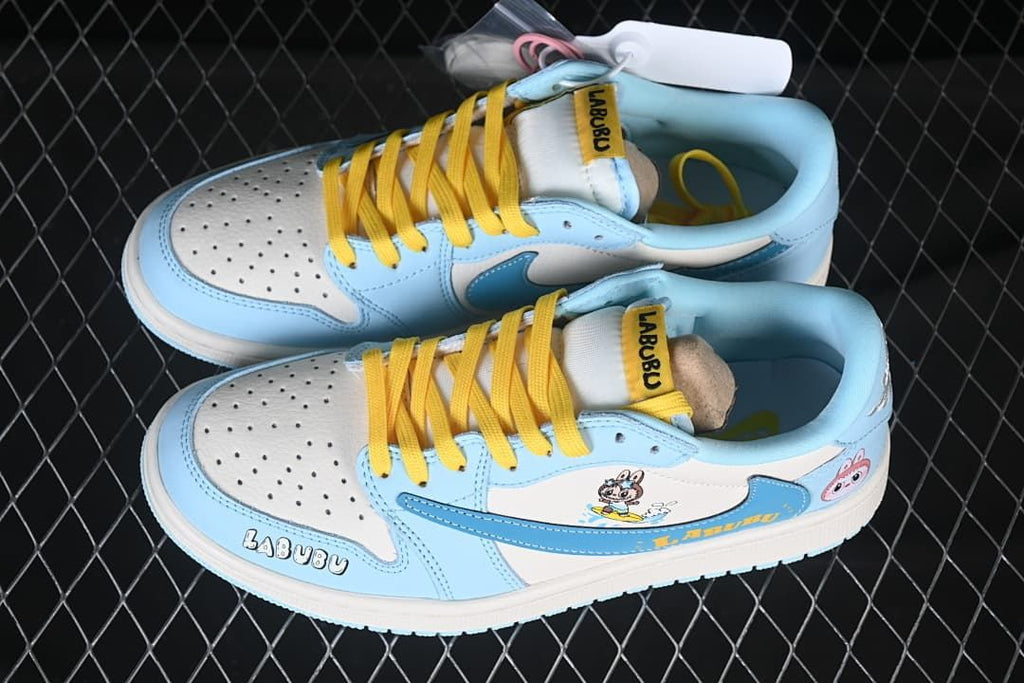Top view of a light blue and white sneaker pair with yellow laces, Labubu graphics, and extra laces