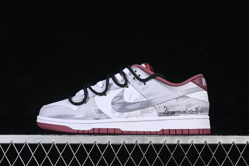 Side view of white low-top Dunk sneakers with gray overlays, burgundy accents, and black cord-style straps