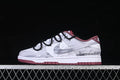 Side view of white low-top Dunk sneakers with gray overlays, burgundy accents, and black cord-style straps