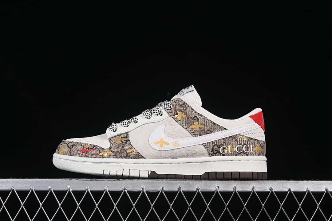 Side view of a low-top sneaker with a white swoosh, brown bee-patterned panels, patterned laces, and red heel accent.