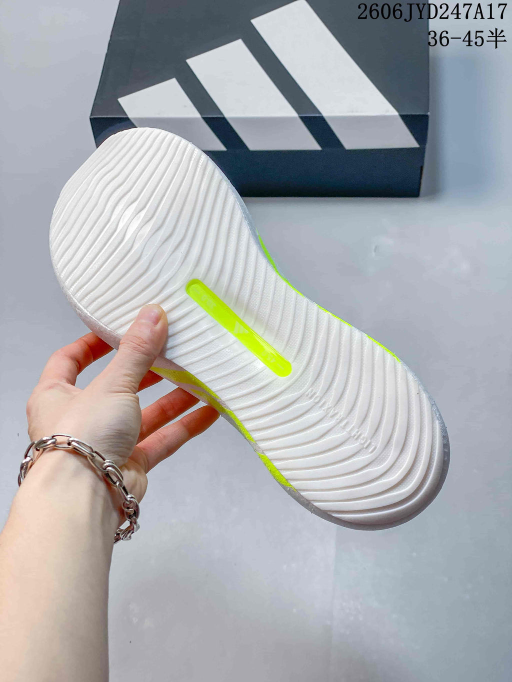 Underside of the sneaker showing a white sole with curved grooves and a neon-lime insert