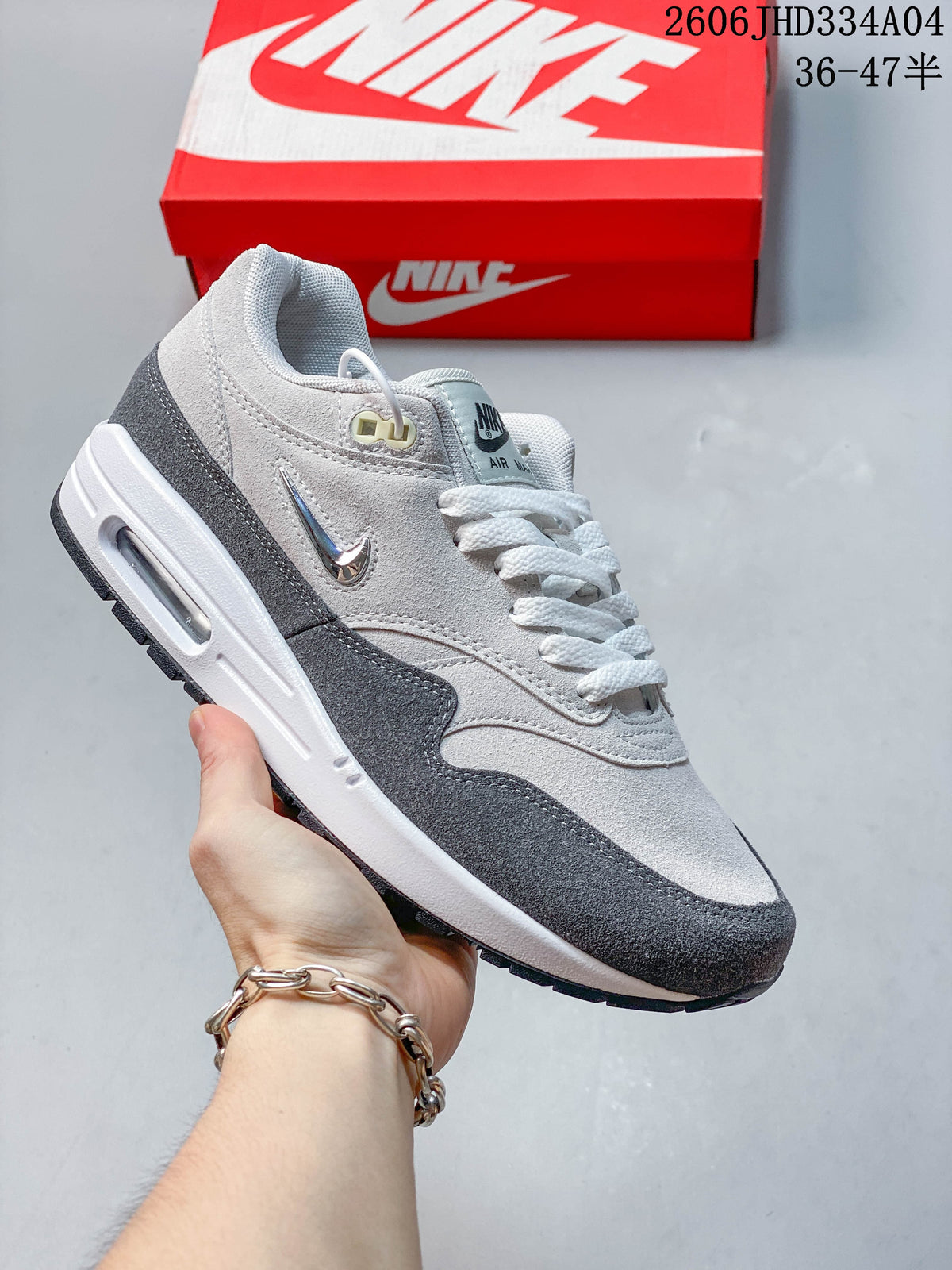 White and gray Nike Air Max 1 sneaker with dark charcoal overlays and a visible Air unit.