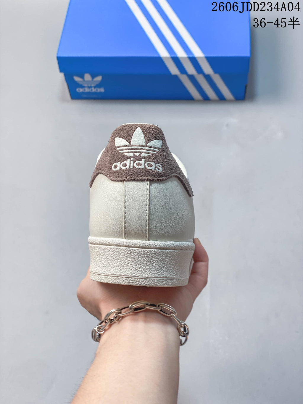 Rear view of an off-white Adidas Superstar sneaker with a brown heel tab.