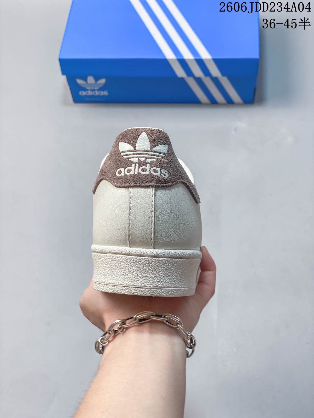 Rear view of an off-white Adidas Superstar sneaker with a brown heel tab.