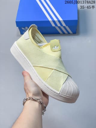 Close side view of a pale yellow slip-on shoe with crossed straps and a textured shell toe.