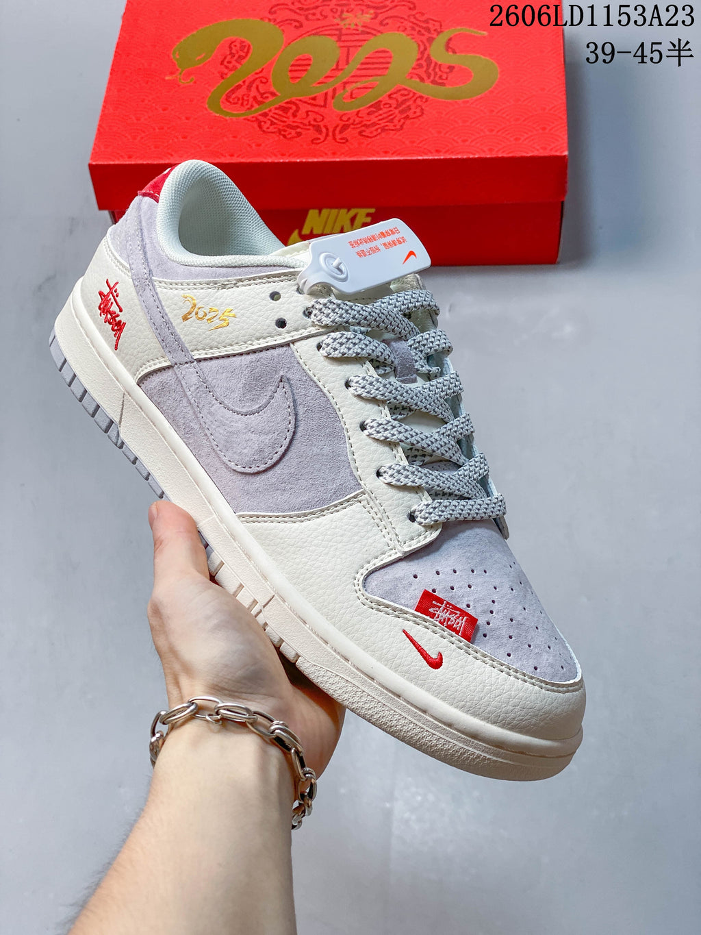 Close view of a light gray and off-white sneaker with gray Swoosh, patterned laces, and red details