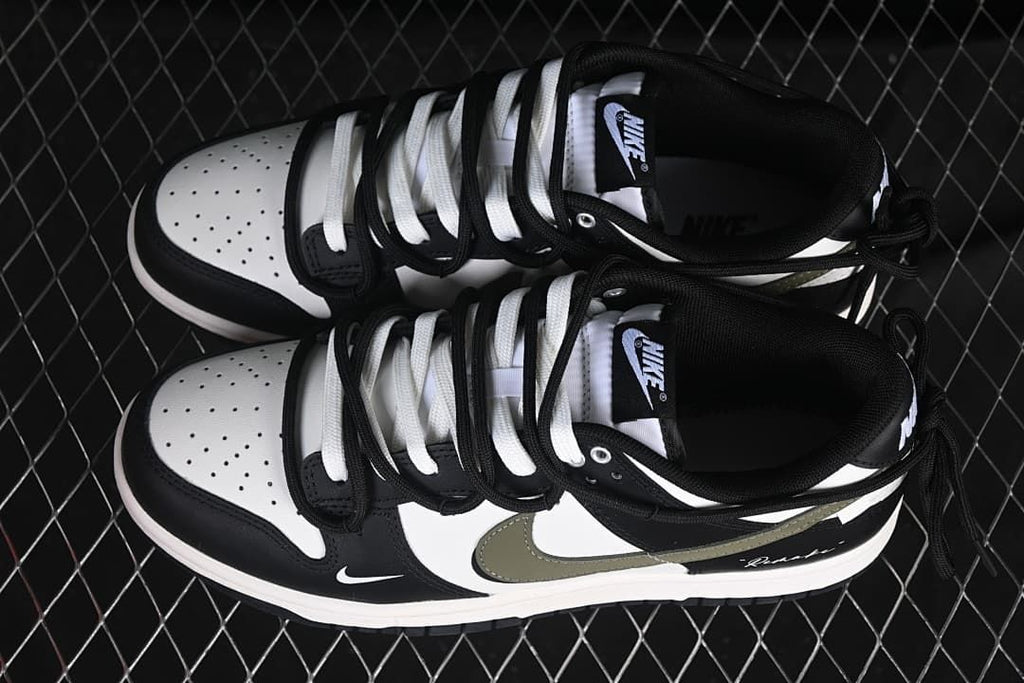 Top view of a pair of black and white Nike SB Dunk Low sneakers with contrasting laces and olive Swooshes