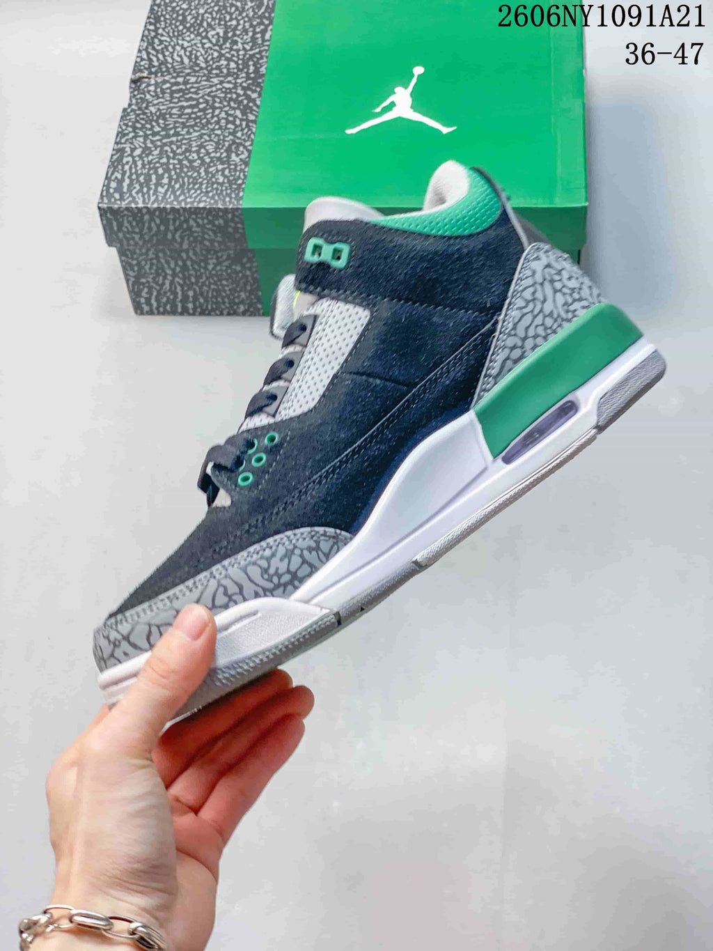 Side view of the navy and grey mid-top sneaker with green accents and patterned overlays