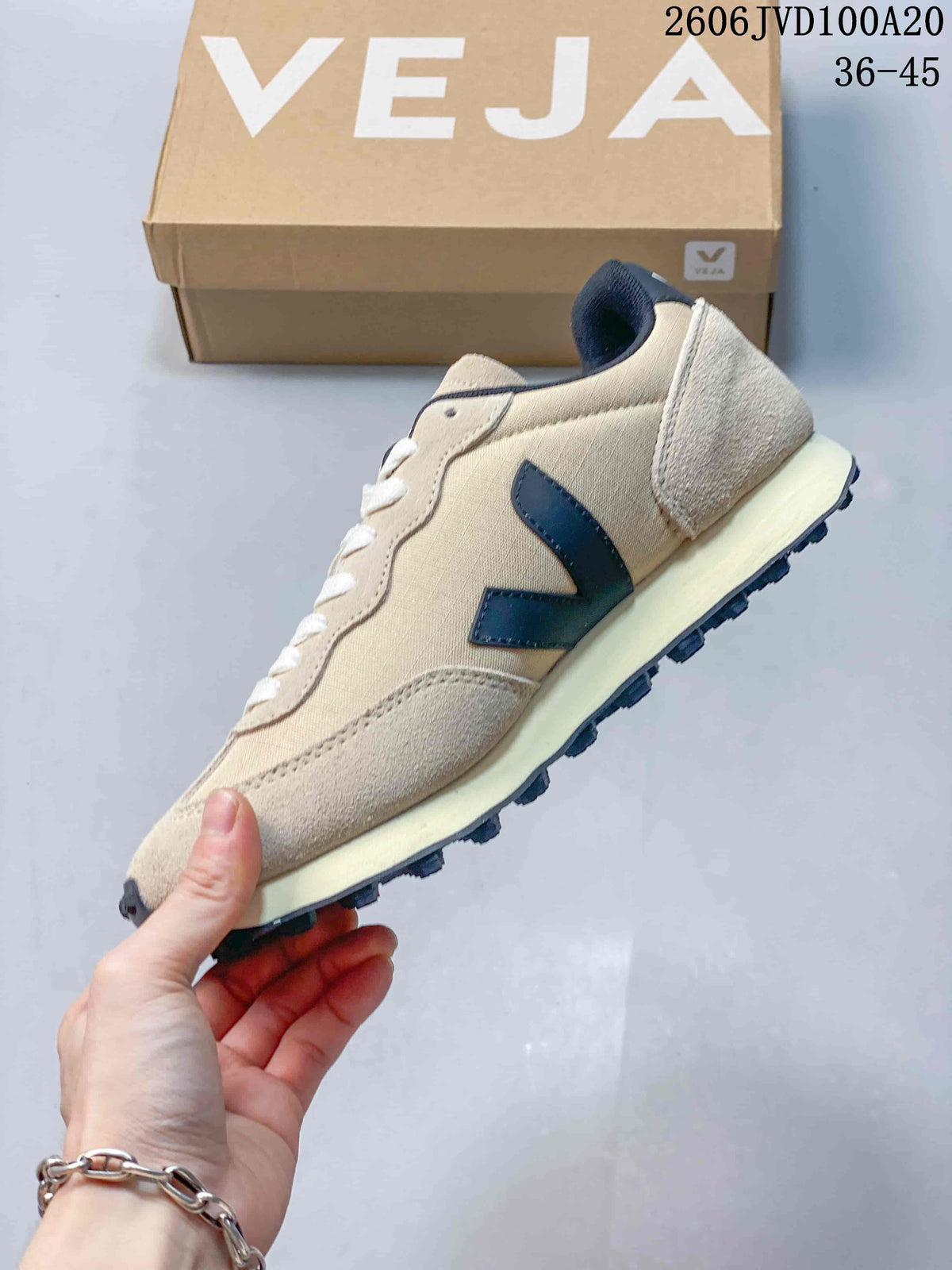 Side view showing the beige upper, navy V detail, and cream-colored midsole