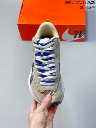 Top view of the sneaker showing layered blue and white laces and the textured beige upper.