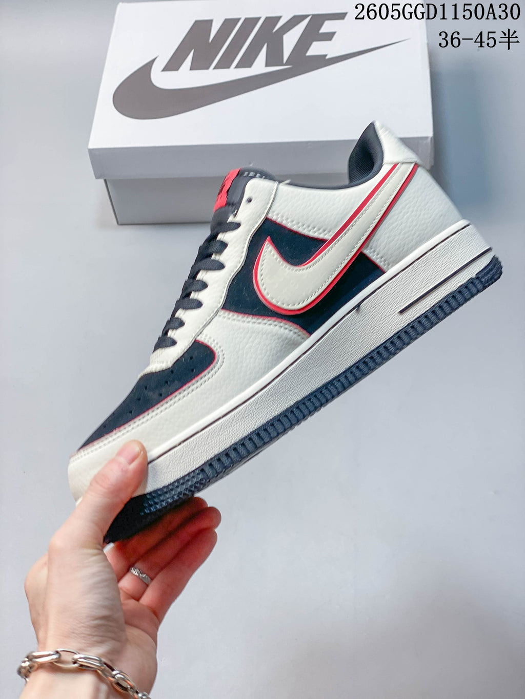 Side profile of the low-top sneaker with cream panels, navy overlays and red trim
