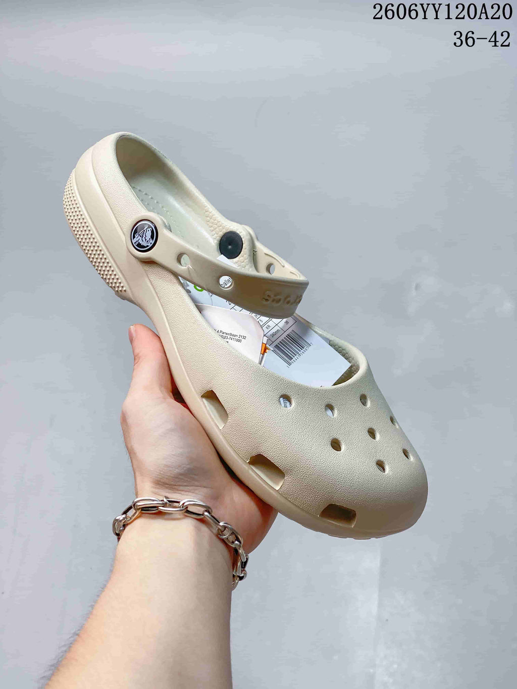 Angled view of the cream clog showing its perforated upper and pivoting strap.
