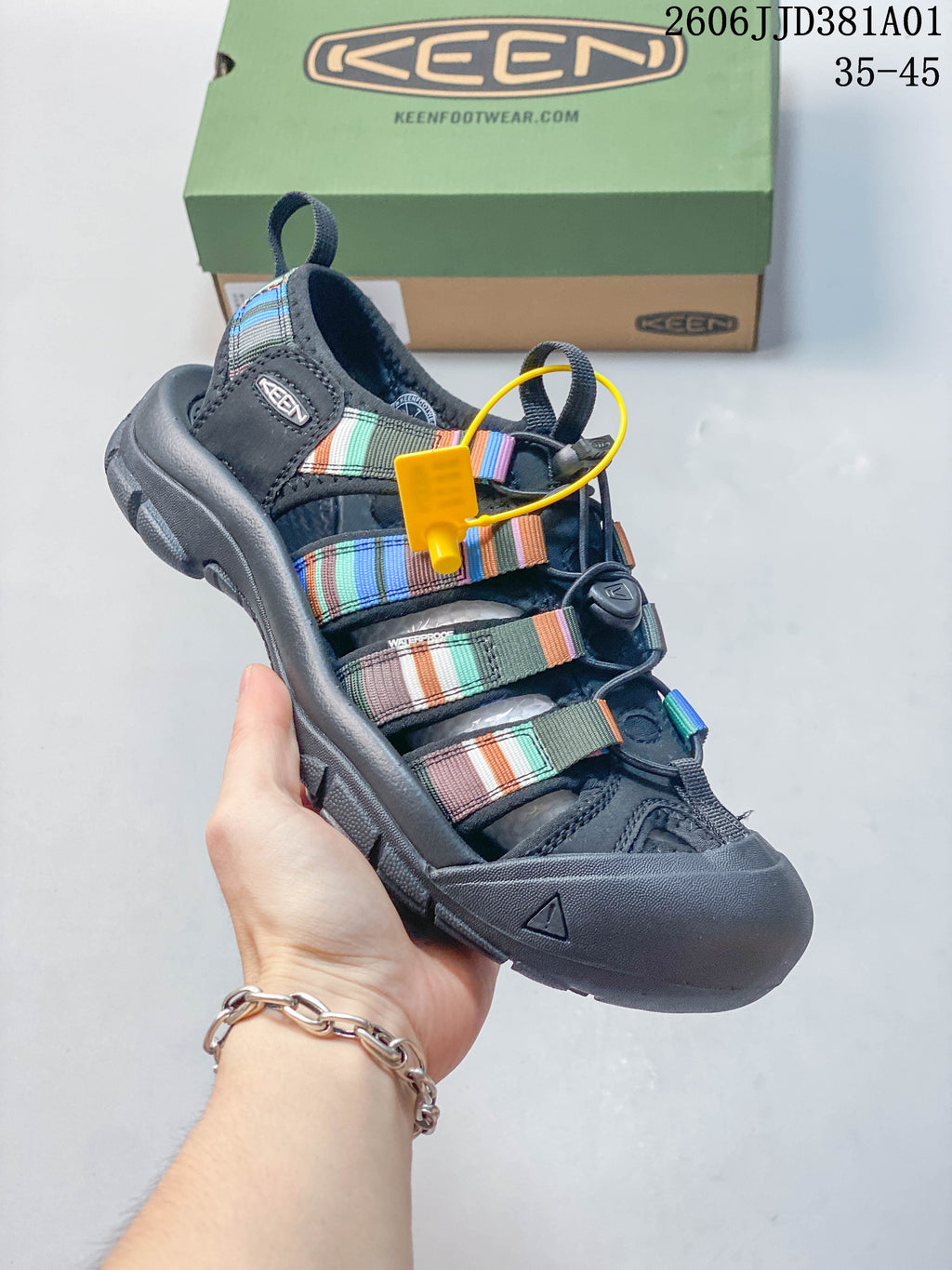 Side view of a dark gray closed-toe sandal with multicolor straps and bungee lacing