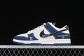 Side view of a white and navy low-top sneaker with a patterned denim-look swoosh and monogram-style panels.