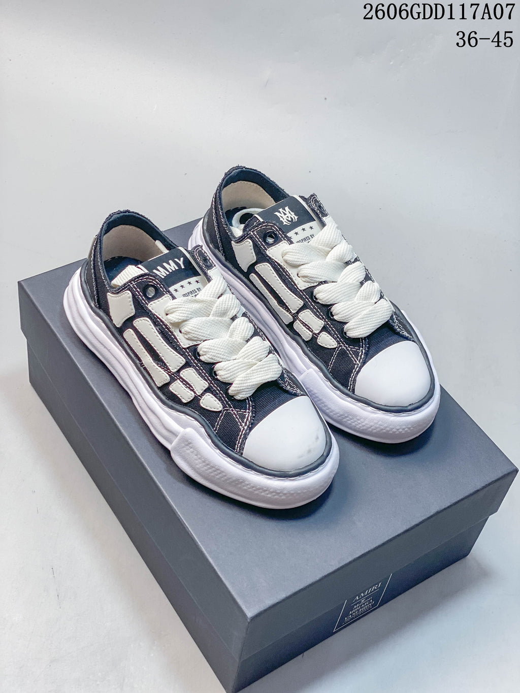 Pair of navy and white Maison Mihara Yasuhiro x AMIRI low-top sneakers on a box