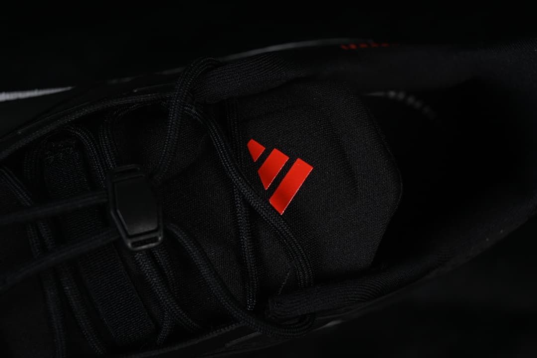 Close-up of the black tongue with a red adidas logo and lace detail.