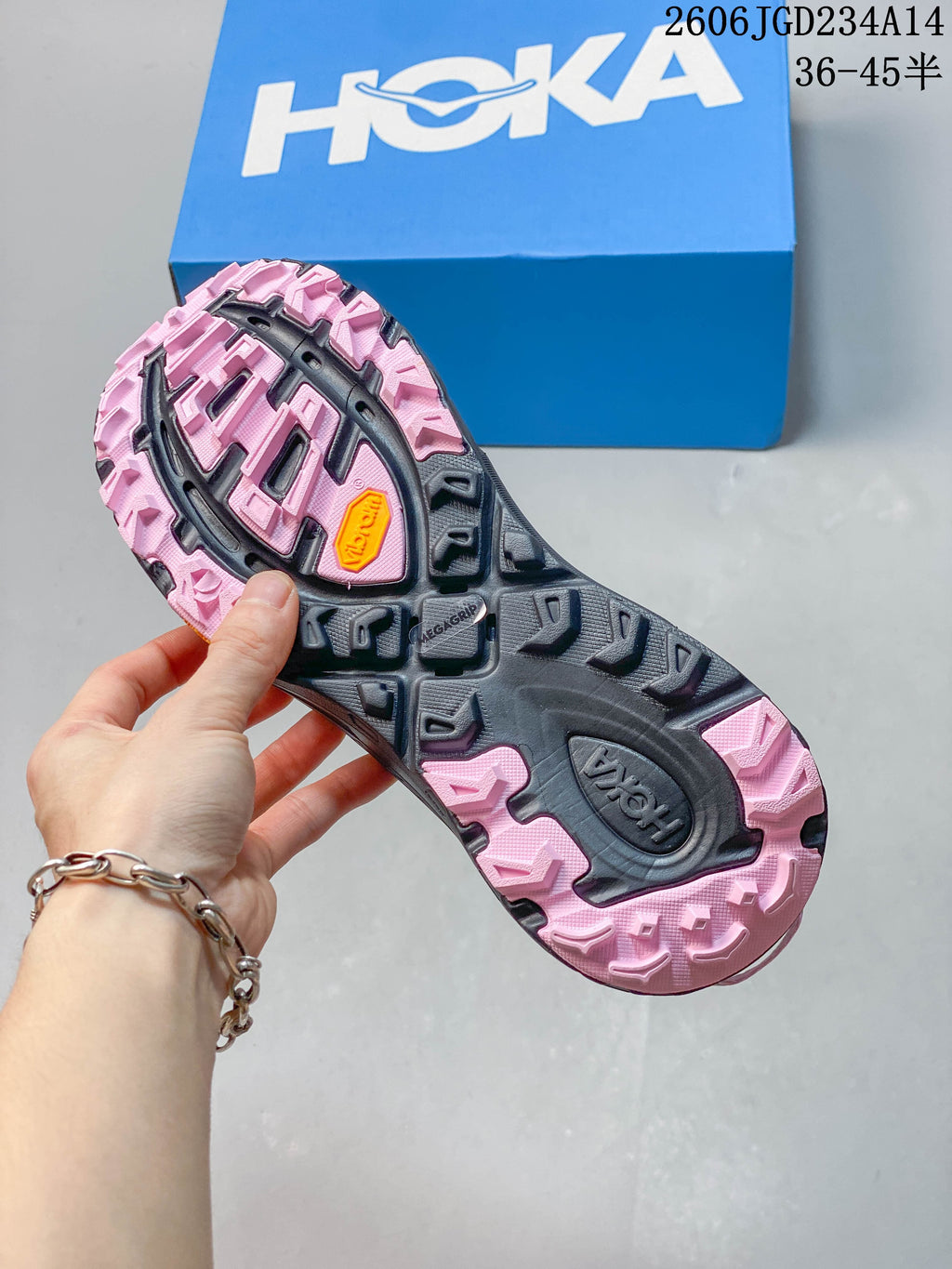Underside of the shoe showing a pink and dark gray lugged outsole
