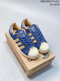 Pair of blue denim-look Adidas Superstar sneakers with gold-tone stripes and cream shell toes on a shoebox