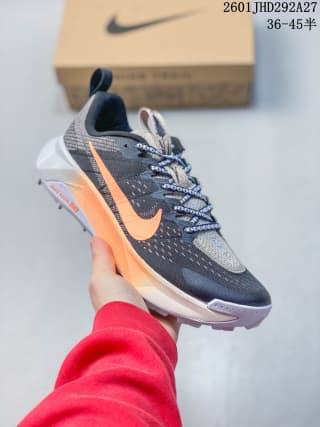 Angled side view showing the dark gray mesh-style upper, orange Swoosh, white midsole, and trail outsole.
