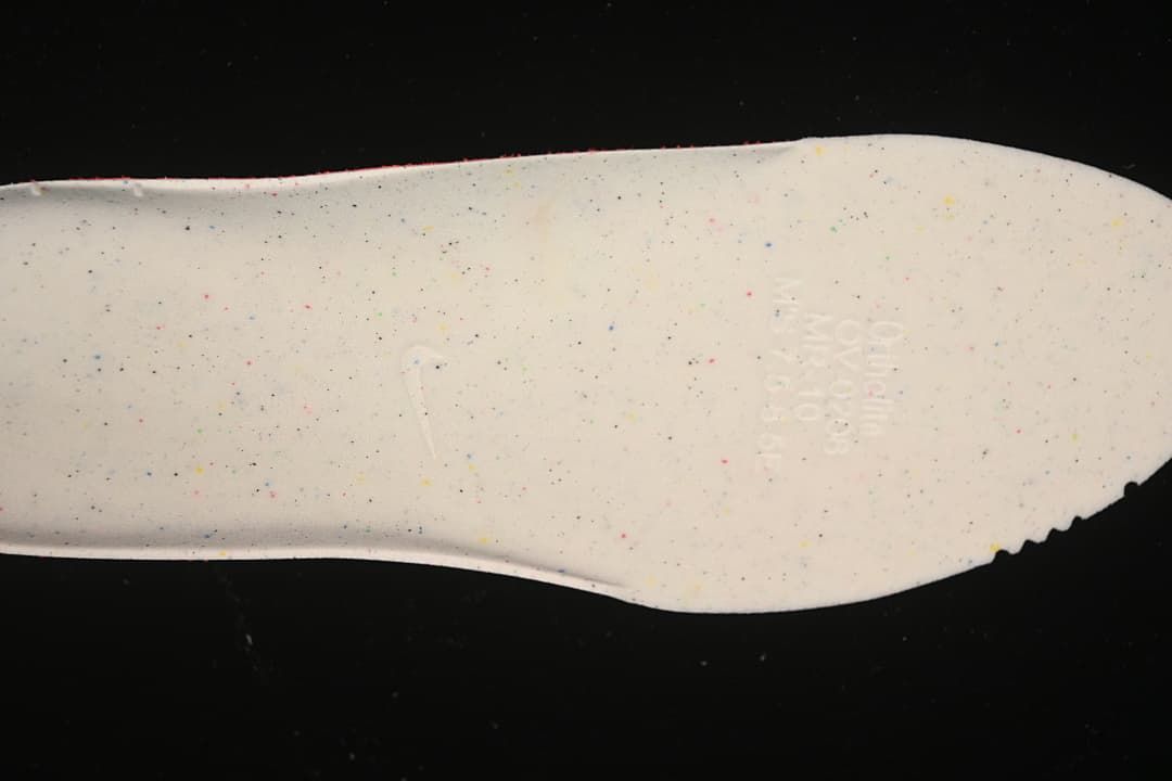 Underside of a white shoe insole with small multicolor speckles.