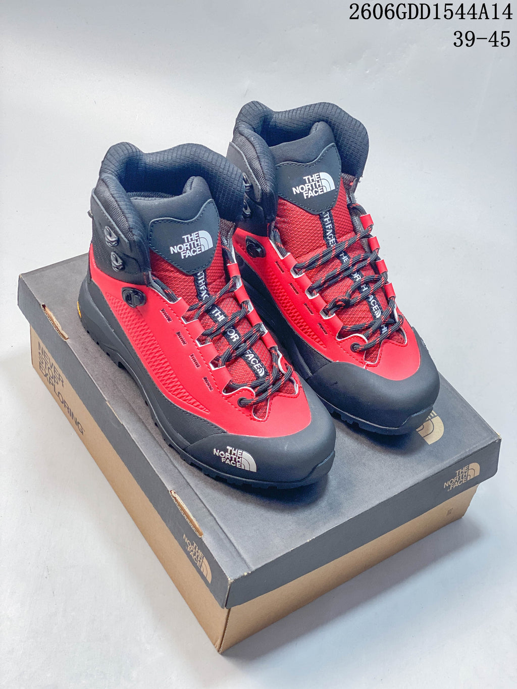 Pair of red and dark gray The North Face Verto Alpine mid hiking boots on a shoebox