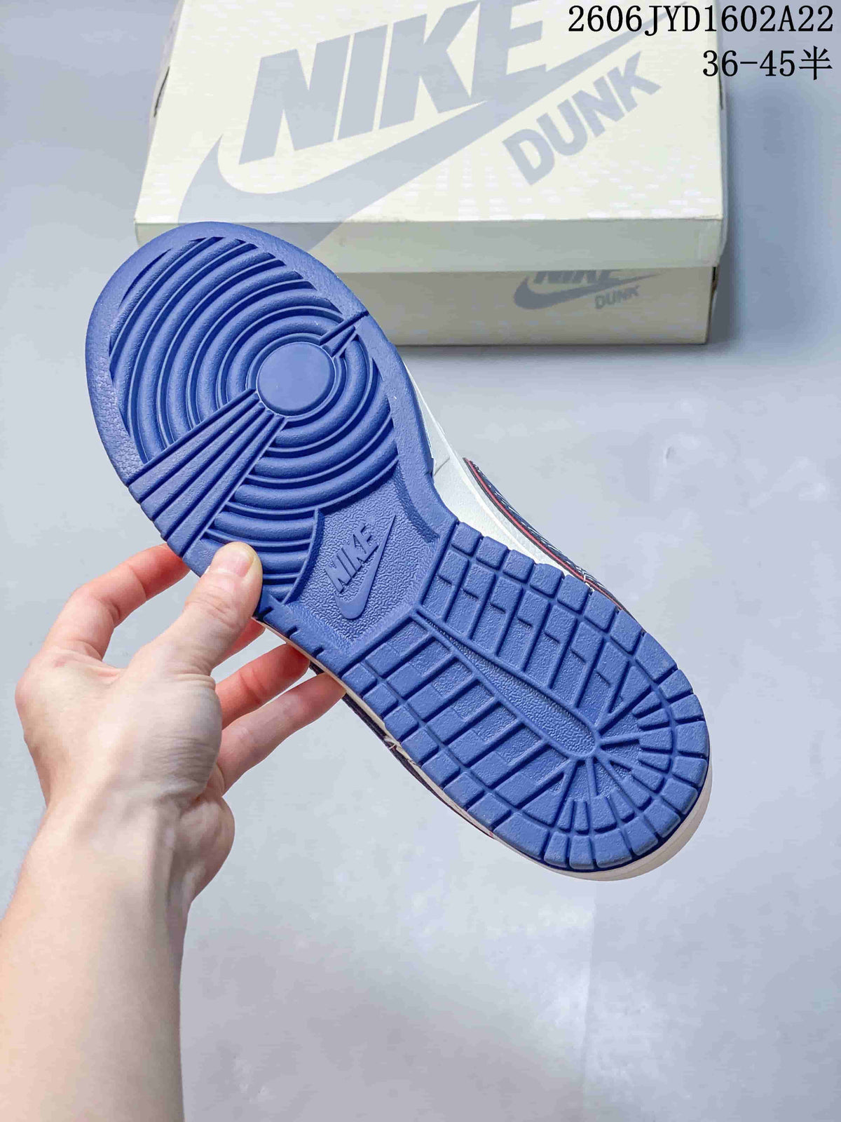 Blue outsole of a Nike Dunk sneaker beside its shoe box