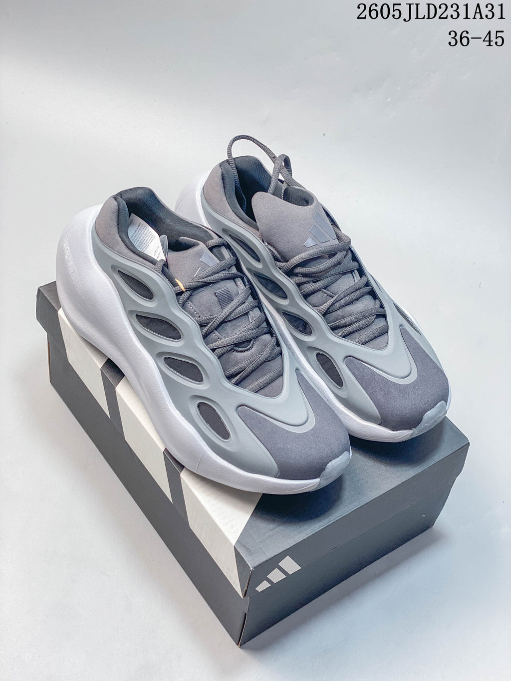 Pair of grey Adidas Hyperboost sneakers on a shoebox, showing the sculpted side panels and white soles.
