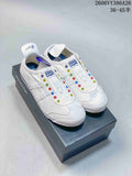 Pair of white Onitsuka Tiger slip-on sneakers with colorful eyelets, shown on a shoe box