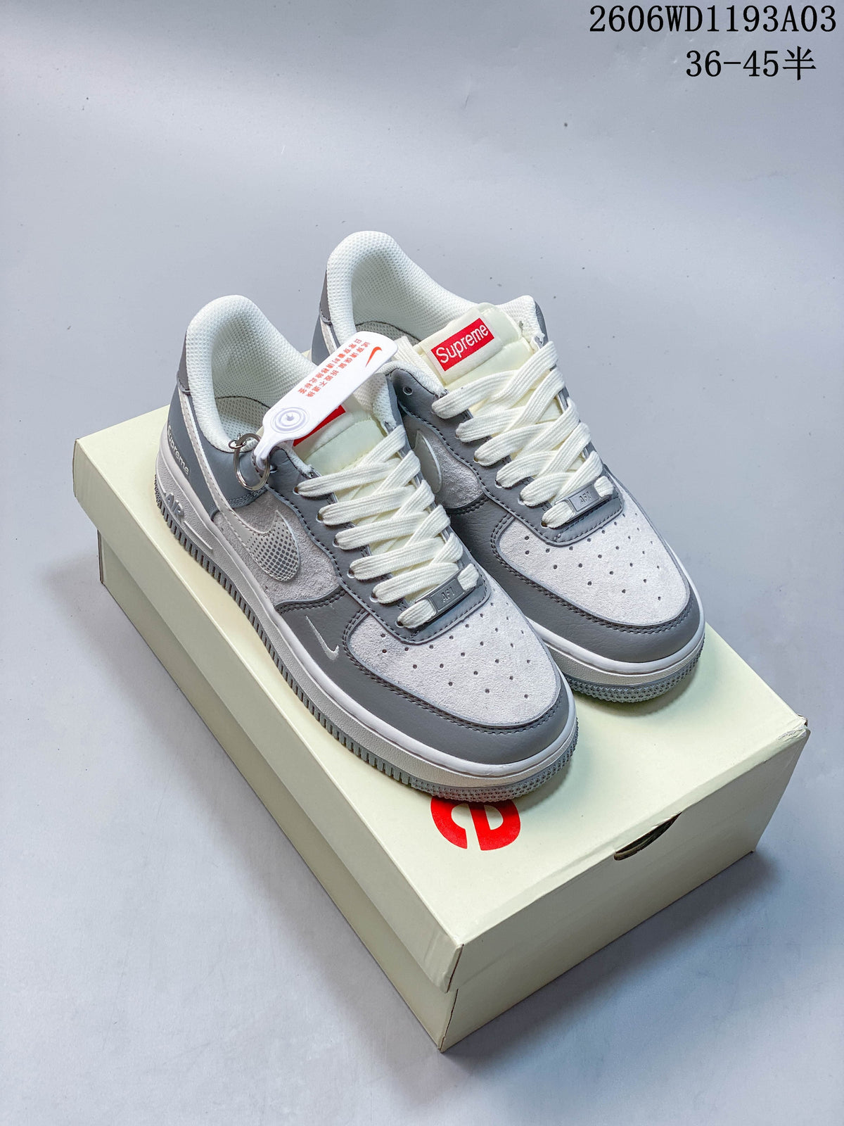 Grey and white low-top sneakers displayed on a branded box