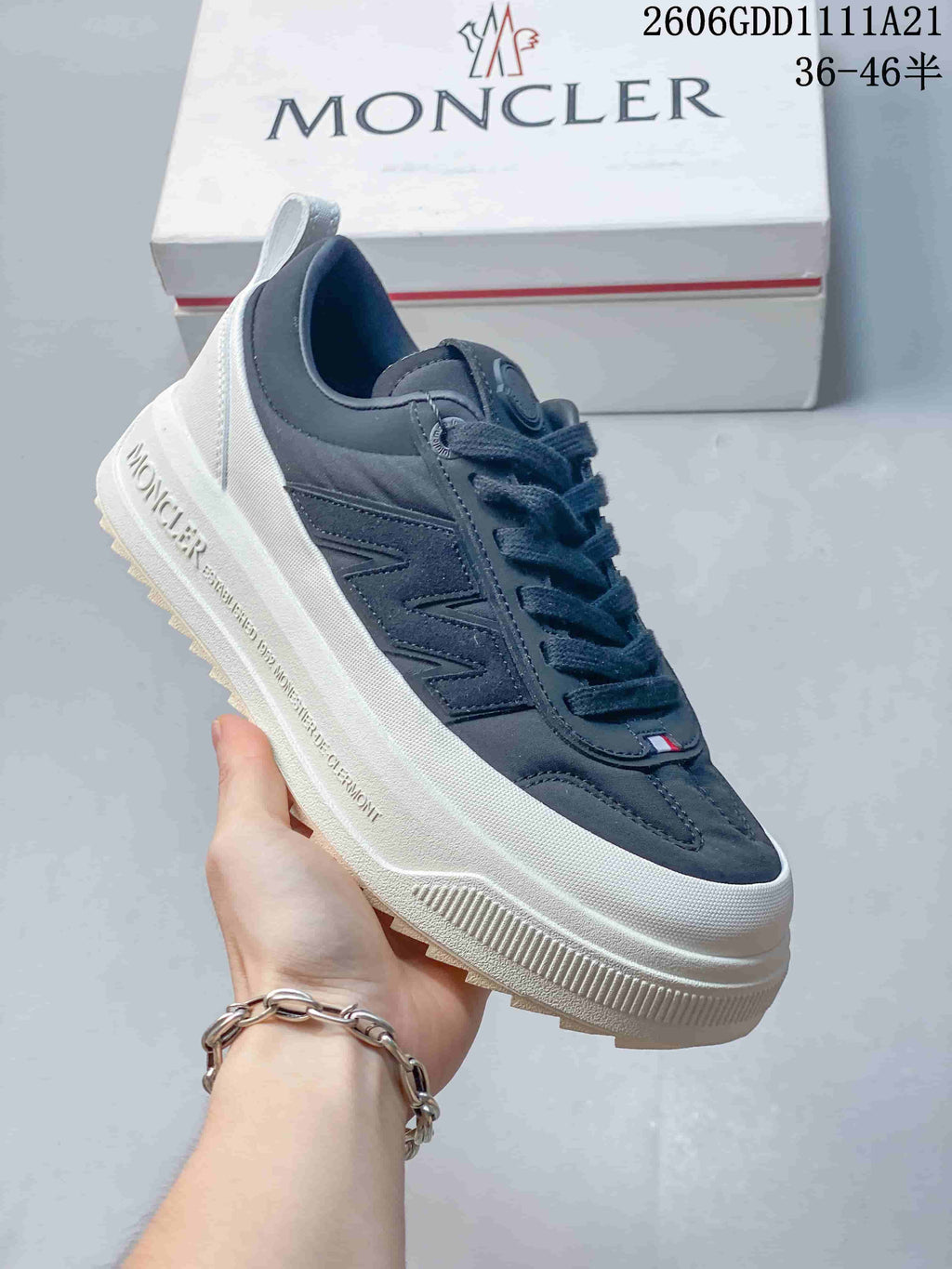 Angled side view of a navy Moncler sneaker with white sole and side detailing