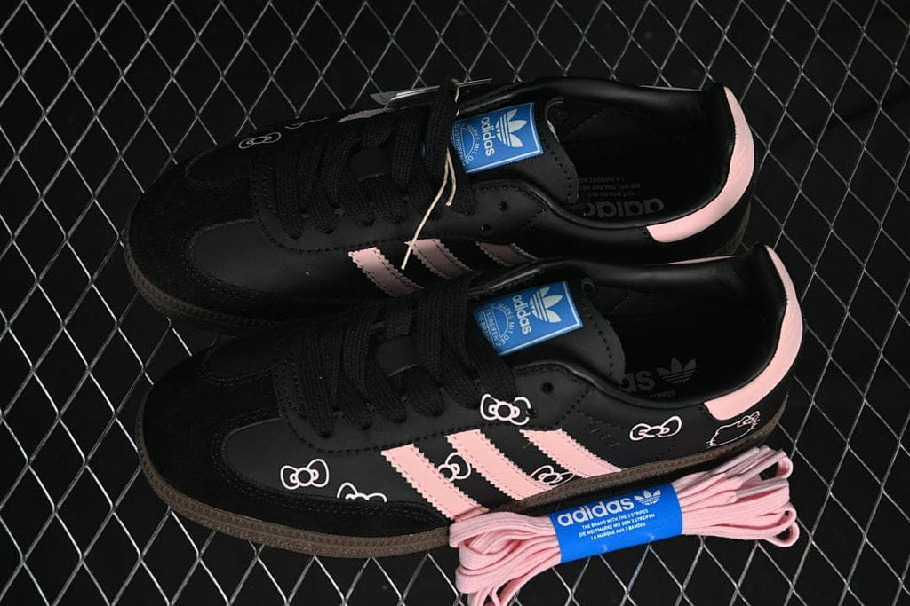 Pair of black and pink sneakers displayed with extra pink laces