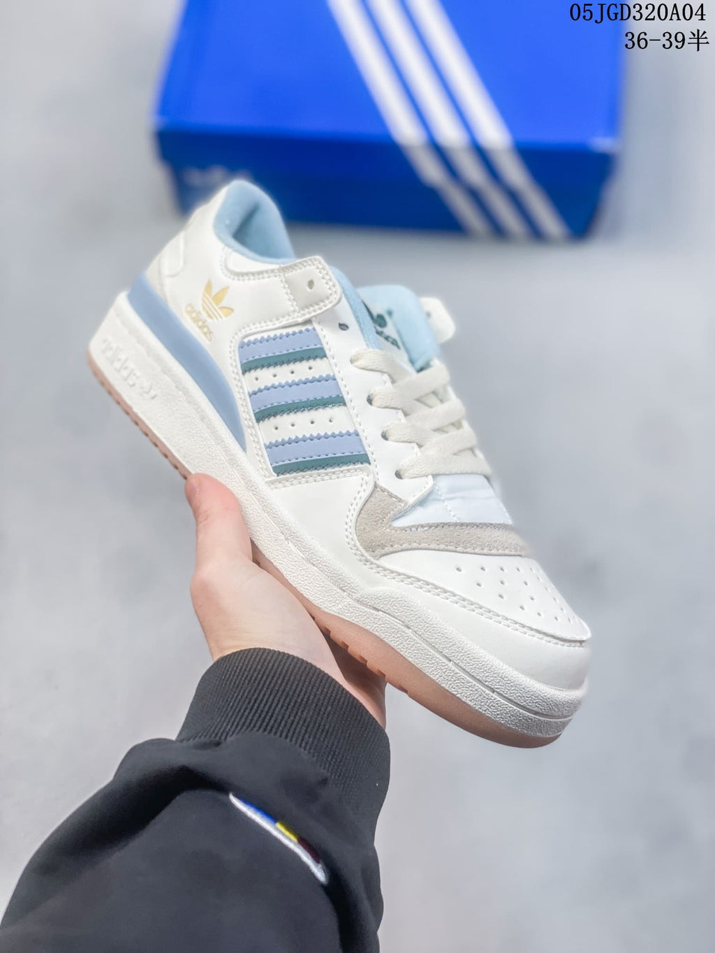 Angled side view of the white sneaker with blue accents, grey overlays, and ankle strap.