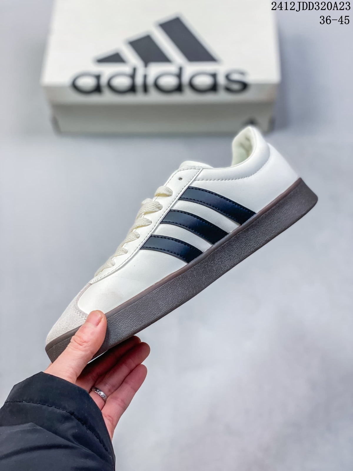 Side view of the white sneaker with navy stripes and dark brown sole
