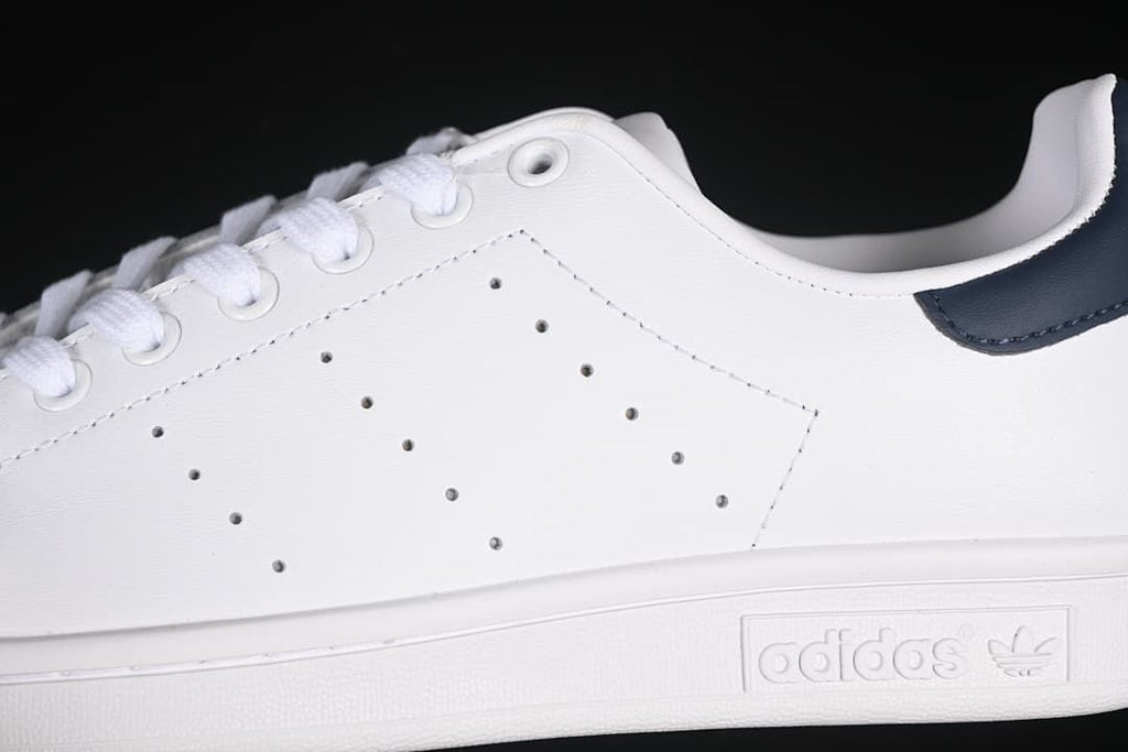 Close-up of perforated white side panels, laces, and embossed sole branding.