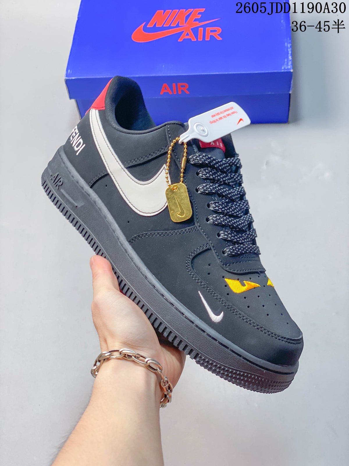 Side view of a dark gray sneaker with a white swoosh, yellow toe accents, and red heel detail