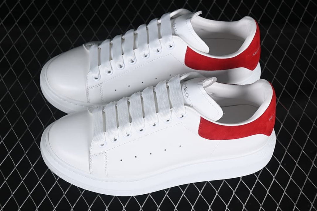 Pair of white low-top sneakers with red heel panels, shown from above.