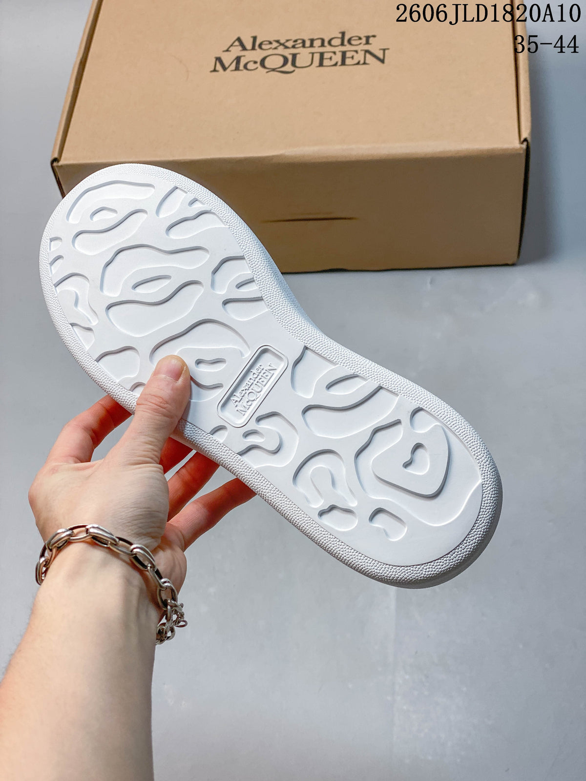 Underside of a white platform sneaker beside a tan box