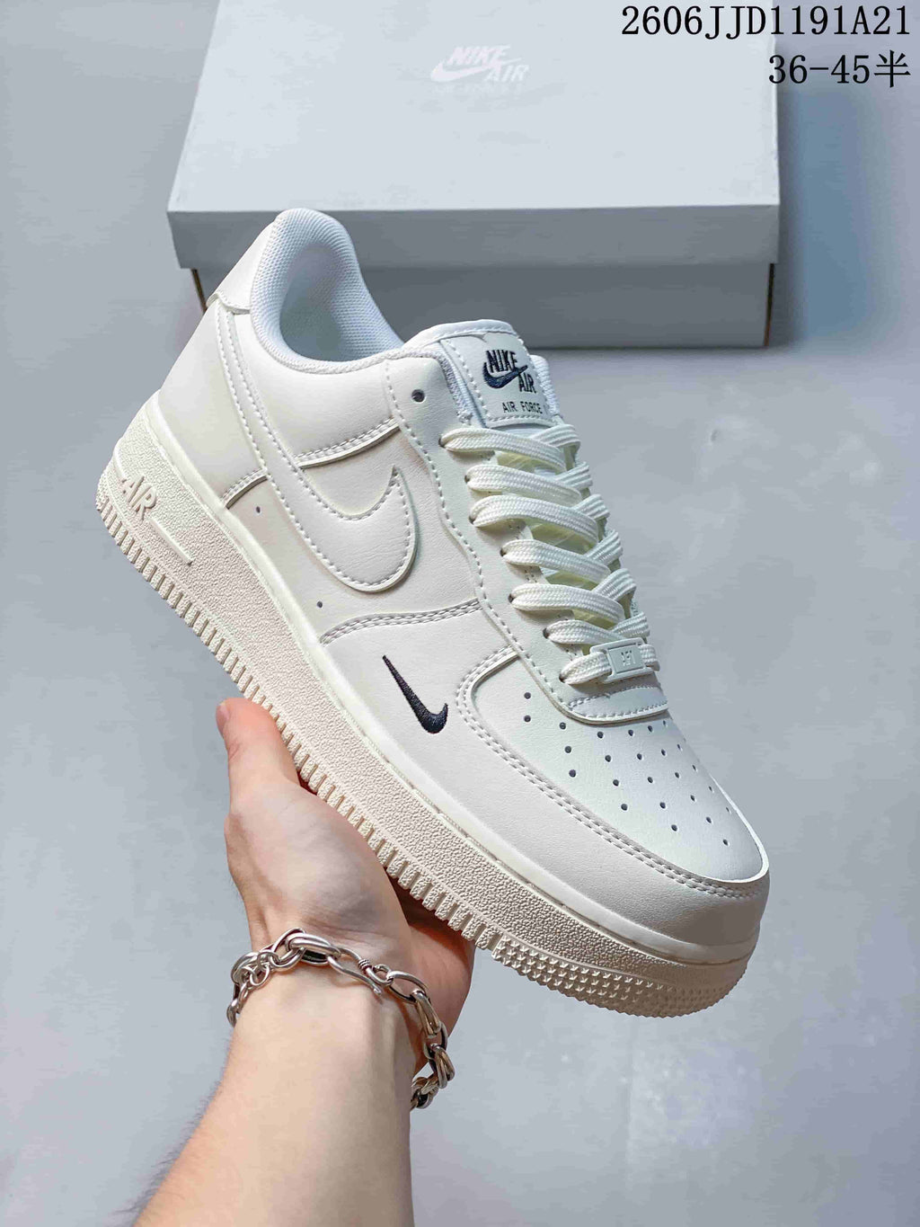 Side view of a white low-top sneaker with a small dark Swoosh and perforated toe.