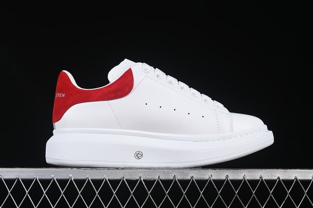 Side profile of a white sneaker with a red heel panel and chunky sole.