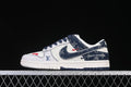 Side view of an off-white and navy Nike SB Dunk Low-style sneaker with denim-style panels and patterned detailing.