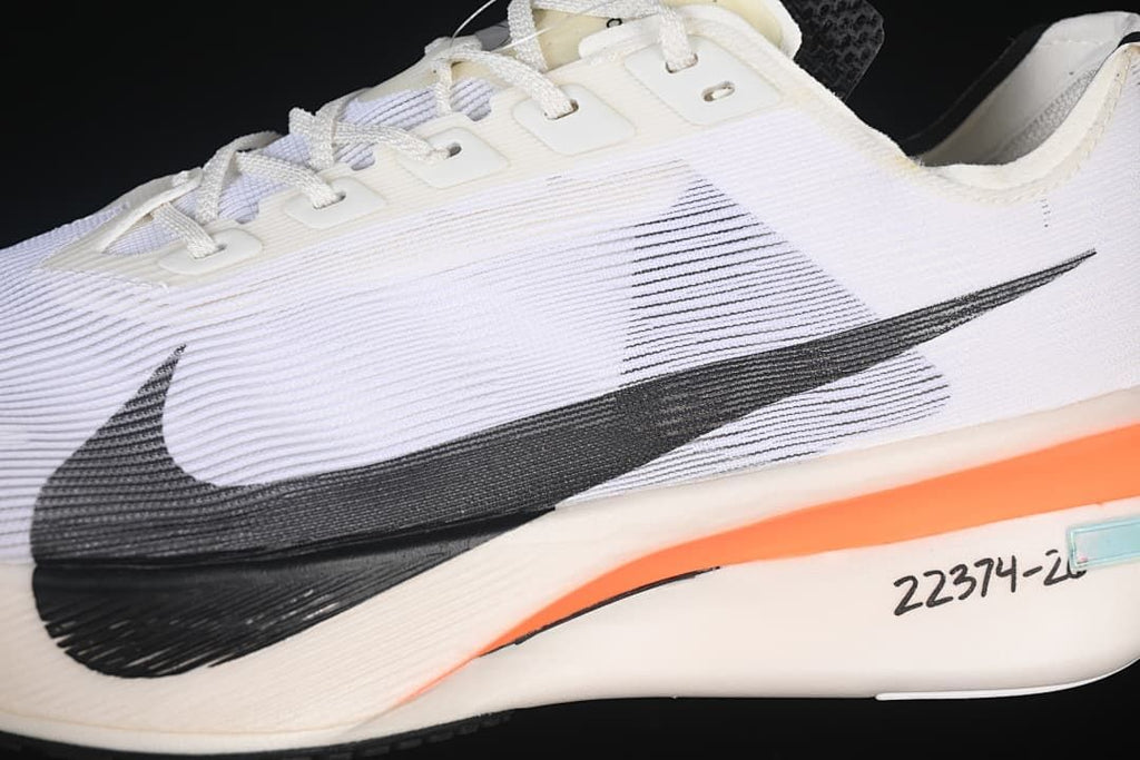 Close-up of the white upper, black Swoosh, laces, and orange midsole detail