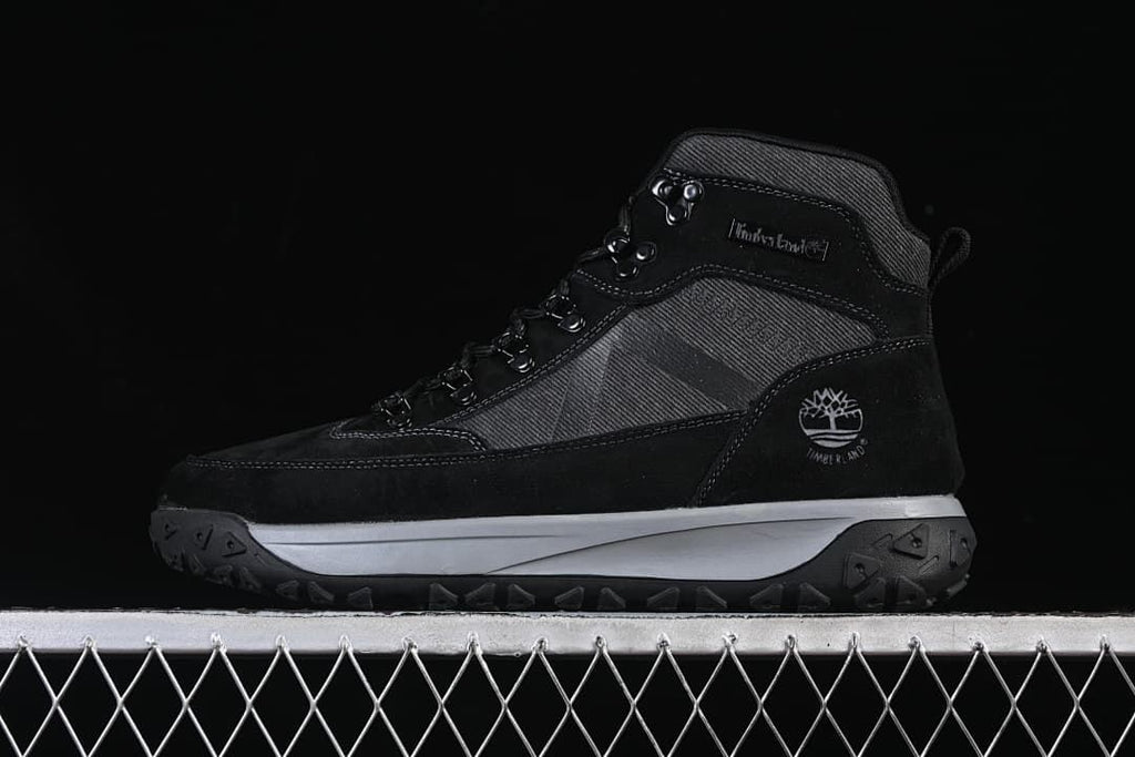 Side view of a black and charcoal Timberland mid-top outdoor boot.