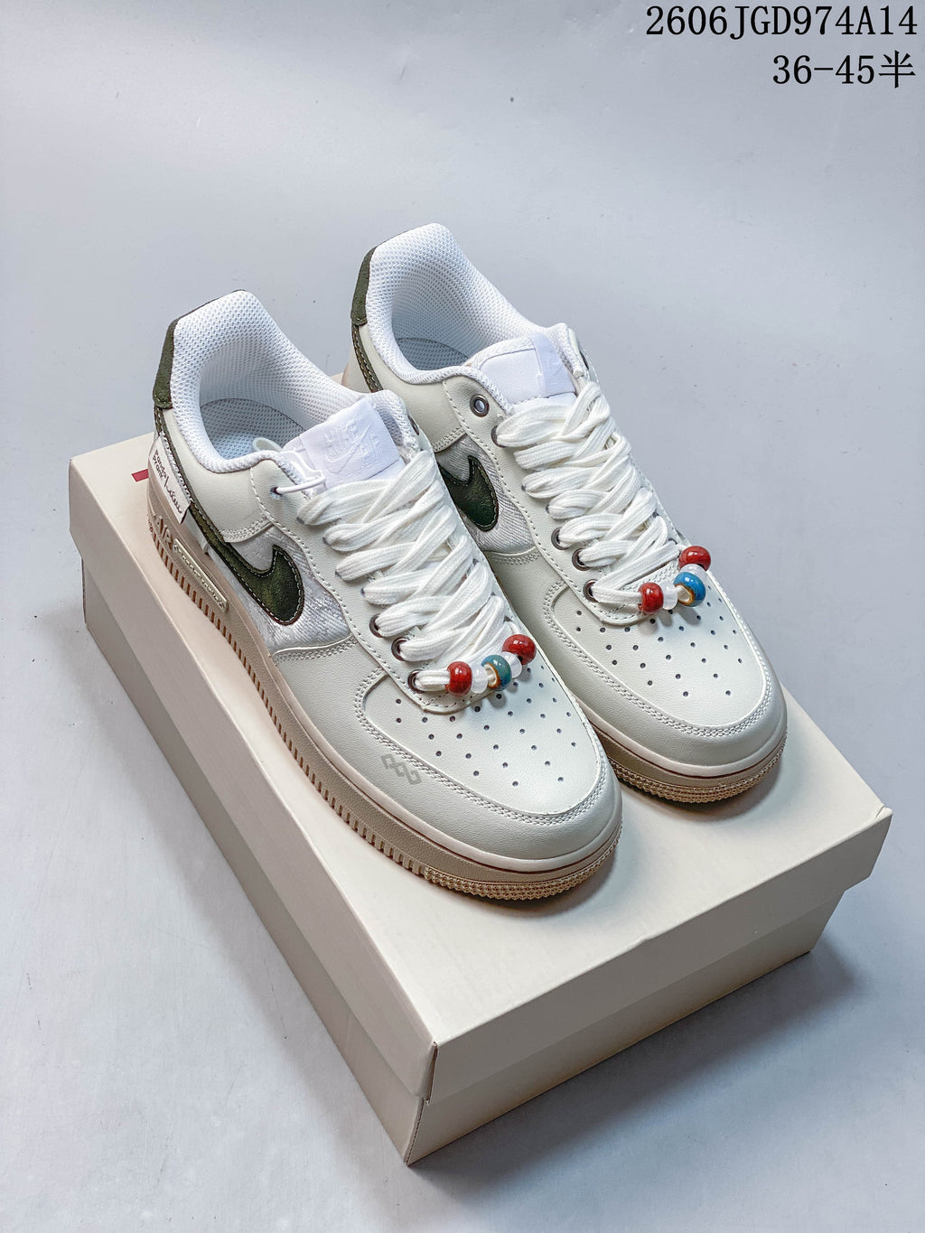 Pair of white low-top sneakers with dark green accents, multicolor lace beads, and raised beige-toned soles